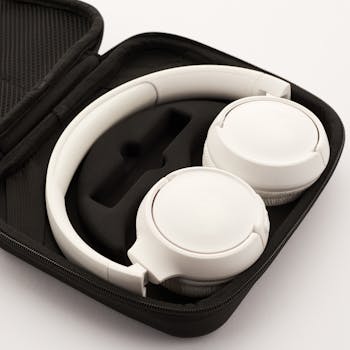 High-quality white wireless headphones resting in a protective carrying case.